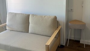 Una stanza dal design essenziale, con un divano in legno e un piccolo sgabello di legno.