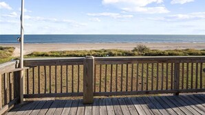 Eine Holzterrasse mit Blick auf Strand und Meer.