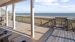 Eine Holzterrasse mit Blick auf Strand und Meer.