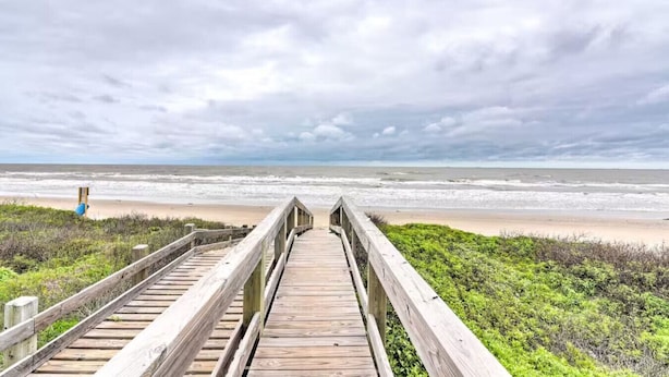 A wooden boardwalk leading to a beach with overcast skies. - Family Haven with Fireplace, Garage hangout, and pet friendly (Bolivar Peninsula)