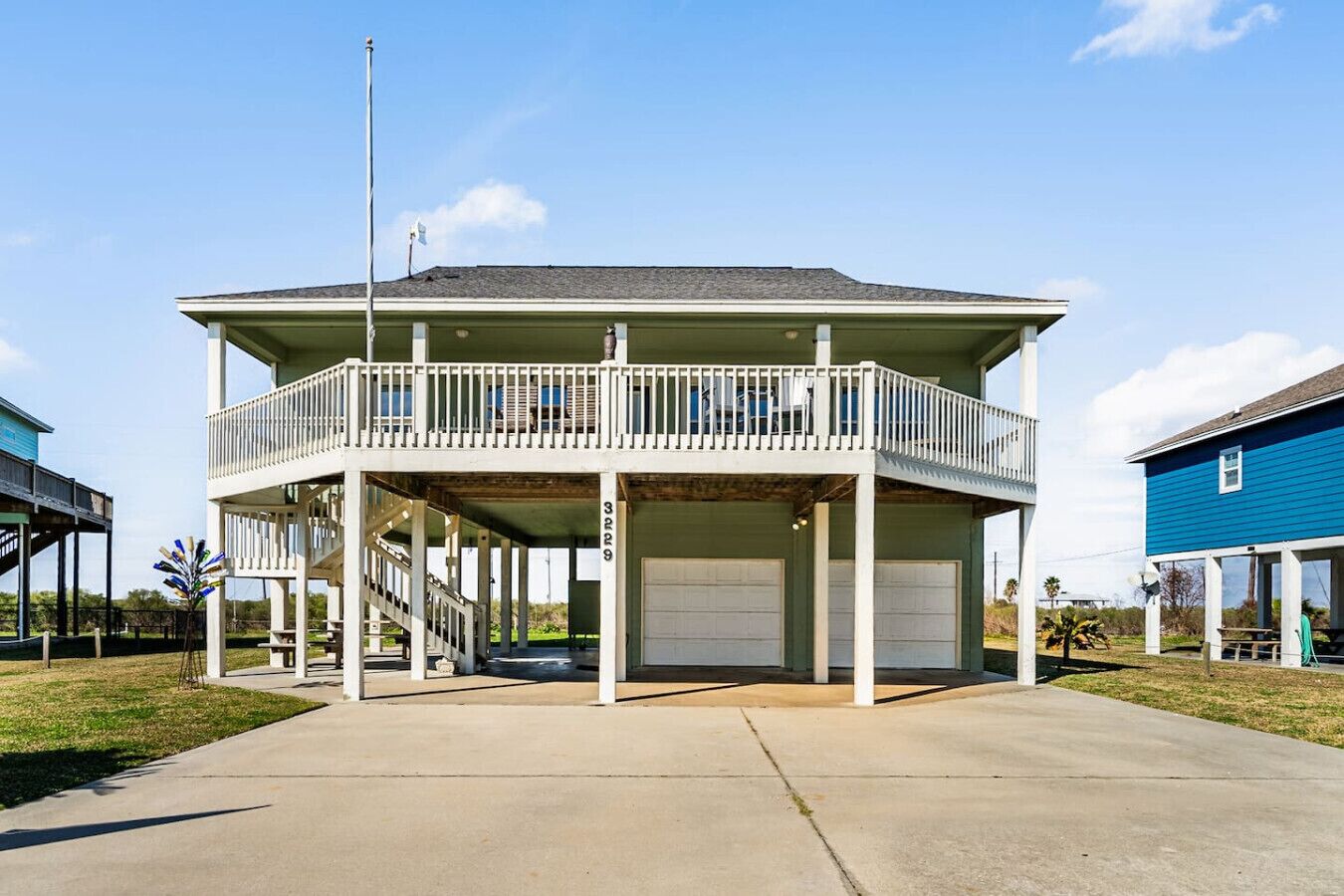 A two-story building with a balcony, a garage, and a flagpole.