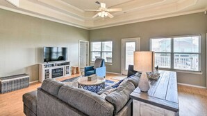 A living room with a sofa, TV, and a ceiling fan. - Family Haven with Fireplace, Garage hangout, and pet friendly (Bolivar Peninsula)