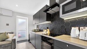 A modern kitchen with a black hexagonal backsplash, a built-in oven, and a wooden countertop. - Cosy Flat in City Centre (Cardiff)