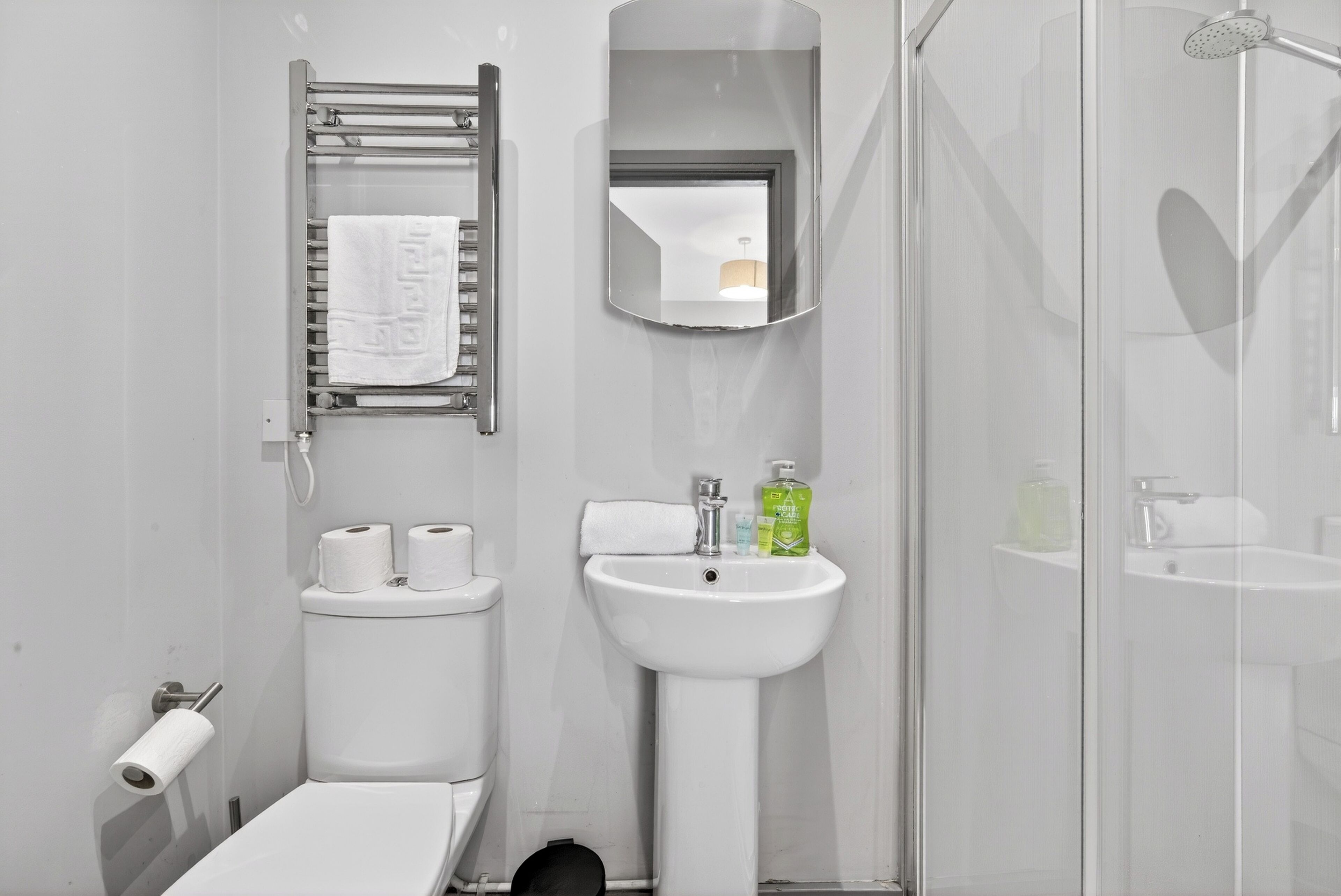Un baño con inodoro, lavamanos, espejo y ducha.