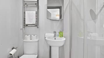Un baño con inodoro, lavamanos, espejo y ducha.