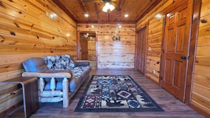 A log cabin interior with a sofa, rug, and wooden doors. - Luxe Cabin, Sleeps 14・Indoor Pool・Hot Tub・Games (Gatlinburg)