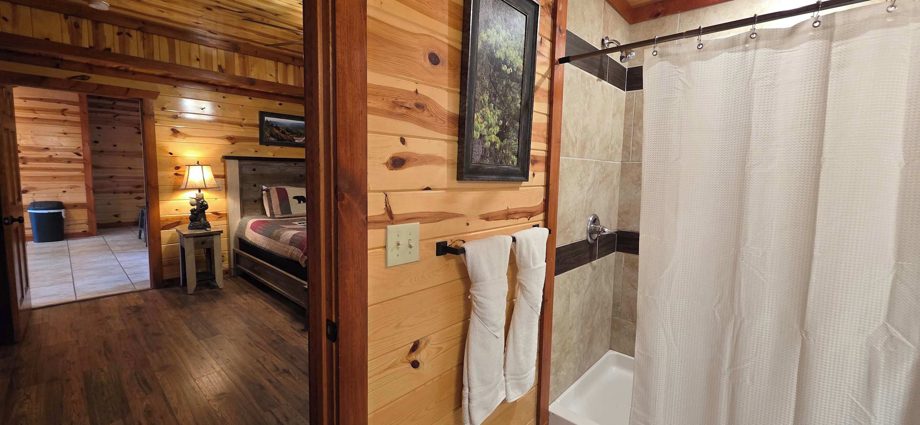 A wooden cabin interior with a bedroom, a bathroom, and a hallway.