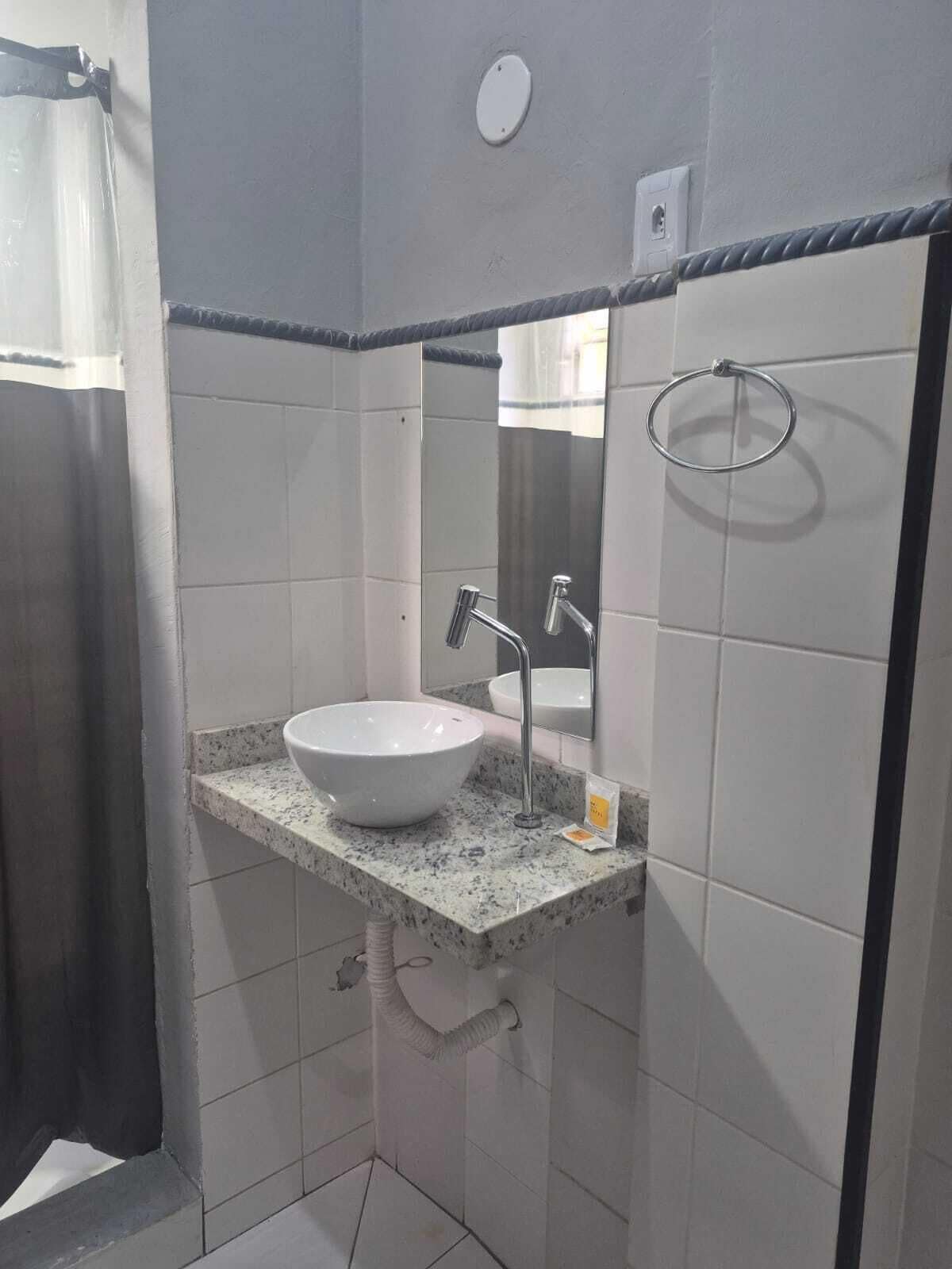 Baño con lavamanos blanco, espejo y argolla para toallas.