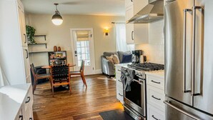 A modern kitchen with stainless steel appliances, wooden flooring, and a dining area with a table and chairs.