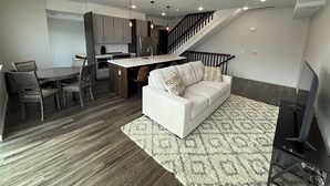 A modern living space with a kitchen, dining area, and a staircase leading to another level.