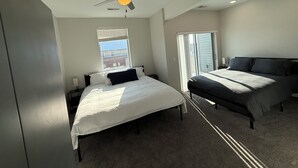A bedroom with two beds, a ceiling fan, a window with blinds, and a view of the outside.