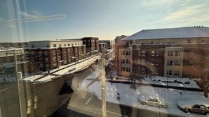 A view of a multi-story building with a snow-covered ground, a clear sky, and a sun shining.