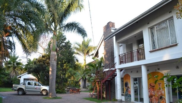 Un edificio de dos pisos con balcón, una chimenea de ladrillo y un mural de cerámica.
