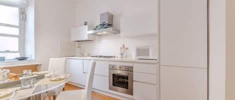 Une cuisine moderne avec des meubles blancs, un four encastré et un four à micro-ondes.