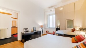 Une chambre à coucher avec un lit, une commode, un miroir, une fenêtre et un radiateur.