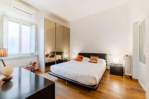 Ein modernes Schlafzimmer mit einem großen Bett, einem Nachttisch, einem Spiegel und einer Heizung.