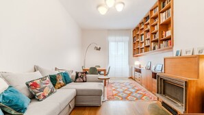 Un salon comprenant un canapé, une cheminée, une bibliothèque et un coin repas.