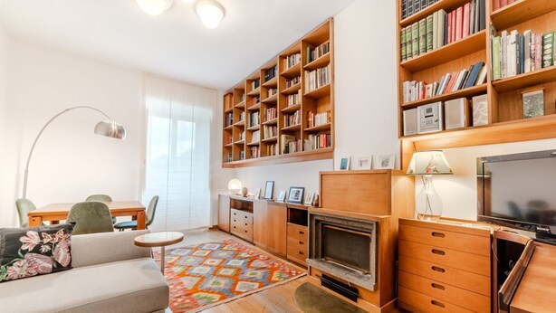 Un salon avec un canapé, une cheminée, une bibliothèque et un téléviseur.
