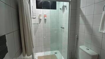 Uma casa de banho pequena com cabine de duche em vidro, sanita e lavatório.