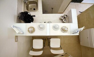 A kitchen with a sink, stove, and two white chairs.
