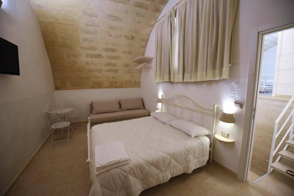 Une chambre à coucher avec un lit, une petite table, un canapé et un escalier.