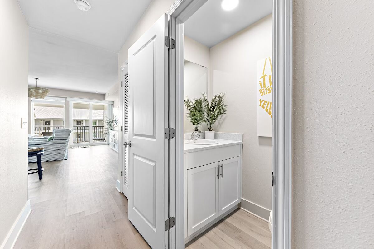 A hallway with a white door, a sink, and a potted plant.