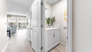 A hallway with a white door, a sink, and a potted plant. - NEW Sea Glass 415 • Balcony • Pool & Ocean Views • Walk to Hangout (Gulf Shores)