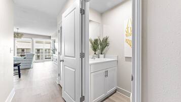 A hallway with a white door, a sink, and a potted plant.