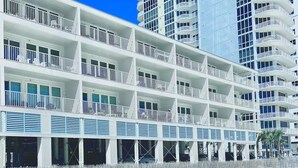 A multi-story hotel with balconies, a pool area, and a beach view. - NEW Sea Glass 415 • Balcony • Pool & Ocean Views • Walk to Hangout (Gulf Shores)
