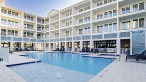 A hotel with a large indoor pool, multiple balconies, and outdoor seating areas. - NEW Sea Glass 415 • Balcony • Pool & Ocean Views • Walk to Hangout (Gulf Shores)