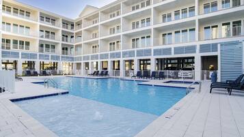 A hotel with a large indoor pool, multiple balconies, and outdoor seating areas.
