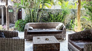 A covered outdoor seating area with wicker furniture and a thatched roof. - Charming 8-bedroom bed & breakfast in beautiful Parajuru with AC (Parajuru)
