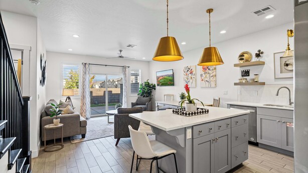 Une cuisine moderne dotée d’un îlot central, de luminaires suspendus et offrant une vue sur l’extérieur.
