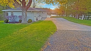 A residential house with a driveway leading to a garage, surrounded by well-maintained lawns and trees.