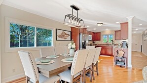 A dining area with a wooden table, beige upholstered chairs, and a pendant light.