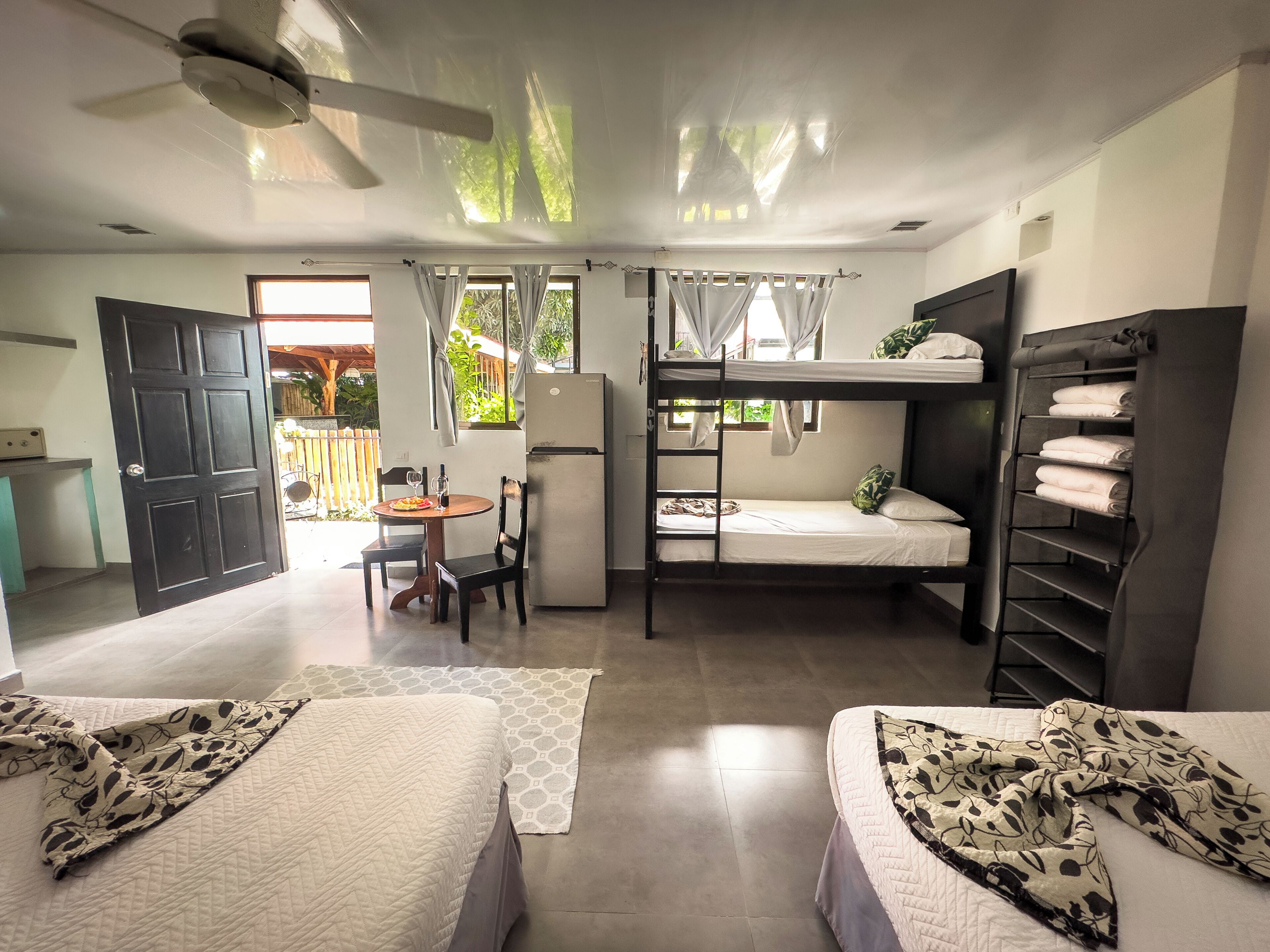 A compact hotel room with bunk beds, a kitchenette, a dining area, and a view of the outdoors.