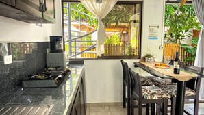 A kitchen with a window, a dining table with chairs, and a small potted plant. - Ela Kosher Hotel and Jewish Center (Jaco)