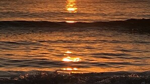 Solnedgang over et roligt hav med en båd i det fjerne.