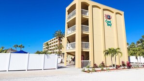 Et hotel med flere etager, altaner, et Coca-Cola skilt og en 'Coral Reef' logo.