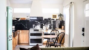 A modern kitchen with a marble countertop, wooden cabinets, and a dining area with a table and chairs.