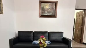 A living room with a black leather sofa, a dark wooden coffee table, and a framed picture on the wall.