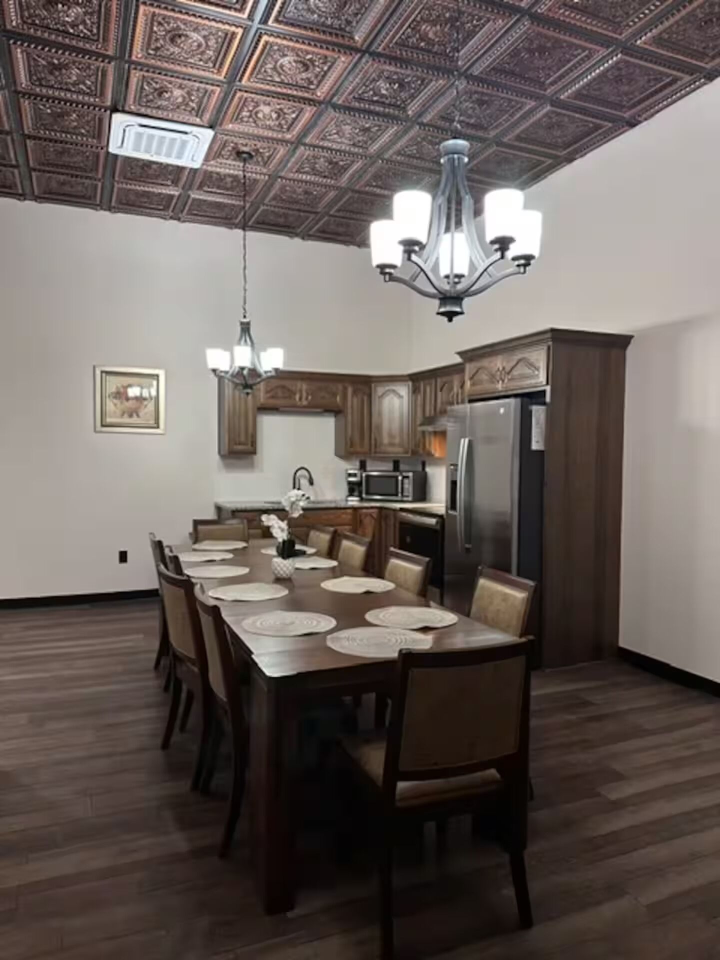 Un comedor con una larga mesa de madera, sillas y una araña.