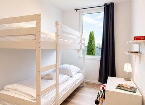 A bunk bed room with a desk, a lamp, and a window with a view of a tree. - House Deichlust Whg.2,Strichweg 165, 27476 Cuxhaven-Döse (Cuxhaven-Döse)