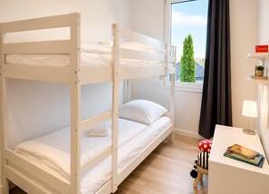 Ein Schlafzimmer mit Etagenbetten, einem Schreibtisch und einer Lampe.