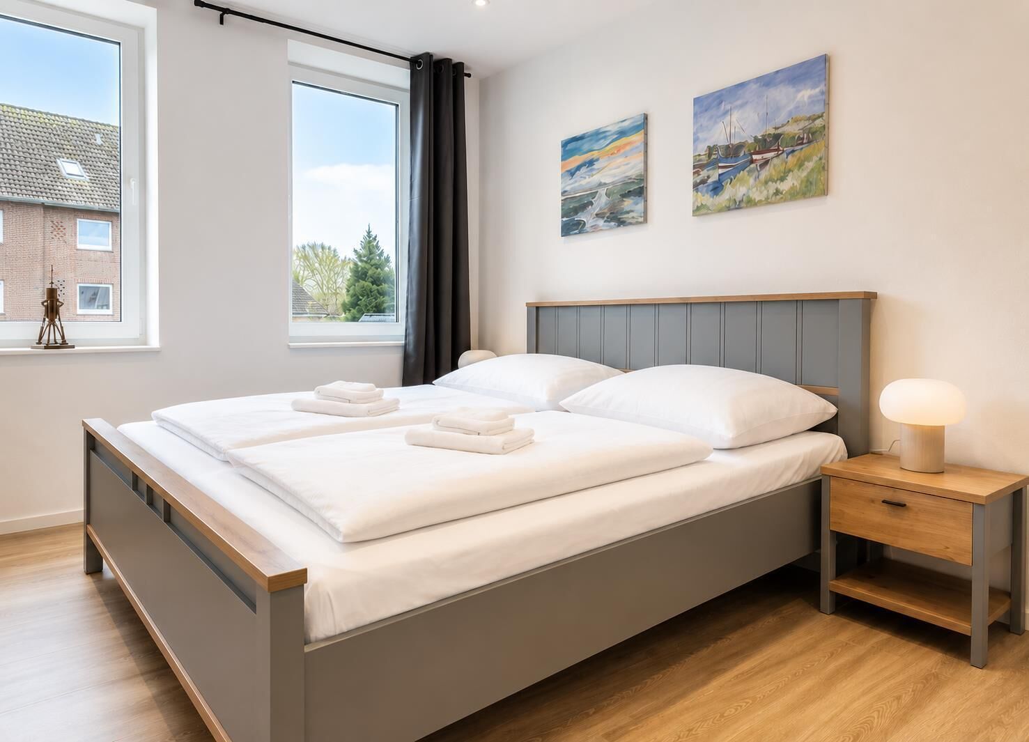 Une chambre à coucher moderne avec un lit, des tables de chevet et des œuvres d’art accrochées au mur.