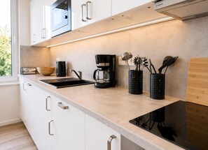 Eine moderne Küche mit weißen Schränken, einer schwarzen Kaffeemaschine und Besteckhaltern.