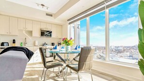 Una cocina moderna con un gran ventanal, un comedor con mesa de vidrio y vistas a la ciudad.