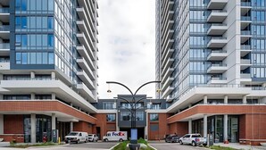 Un edificio moderno con dos secciones altas, una entrada central y un camión de entrega de FedEx estacionado en la parte delantera.