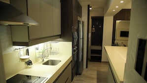 A modern kitchen with stainless steel appliances, a double sink, and a compact layout. - Apartamento Vista Mar em Imbituba (Imbituba)