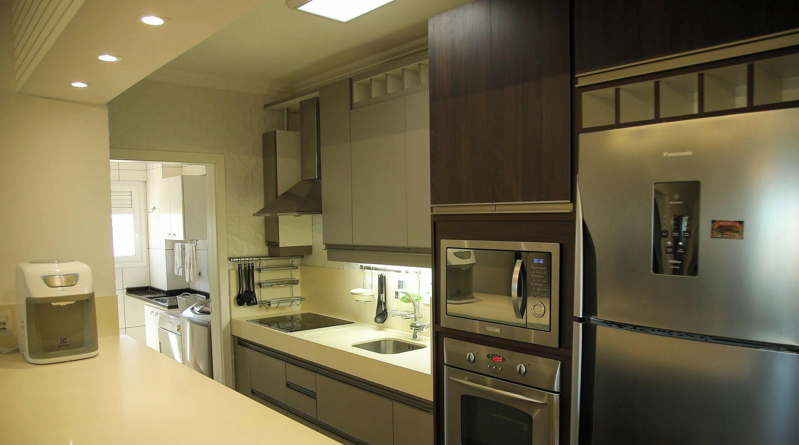 A modern kitchen with stainless steel appliances, including a refrigerator, oven, and microwave. There is a sink with a faucet, and cabinets above the countertop.